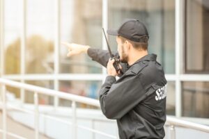 male security guard using portable radio transmitter near building outdoors